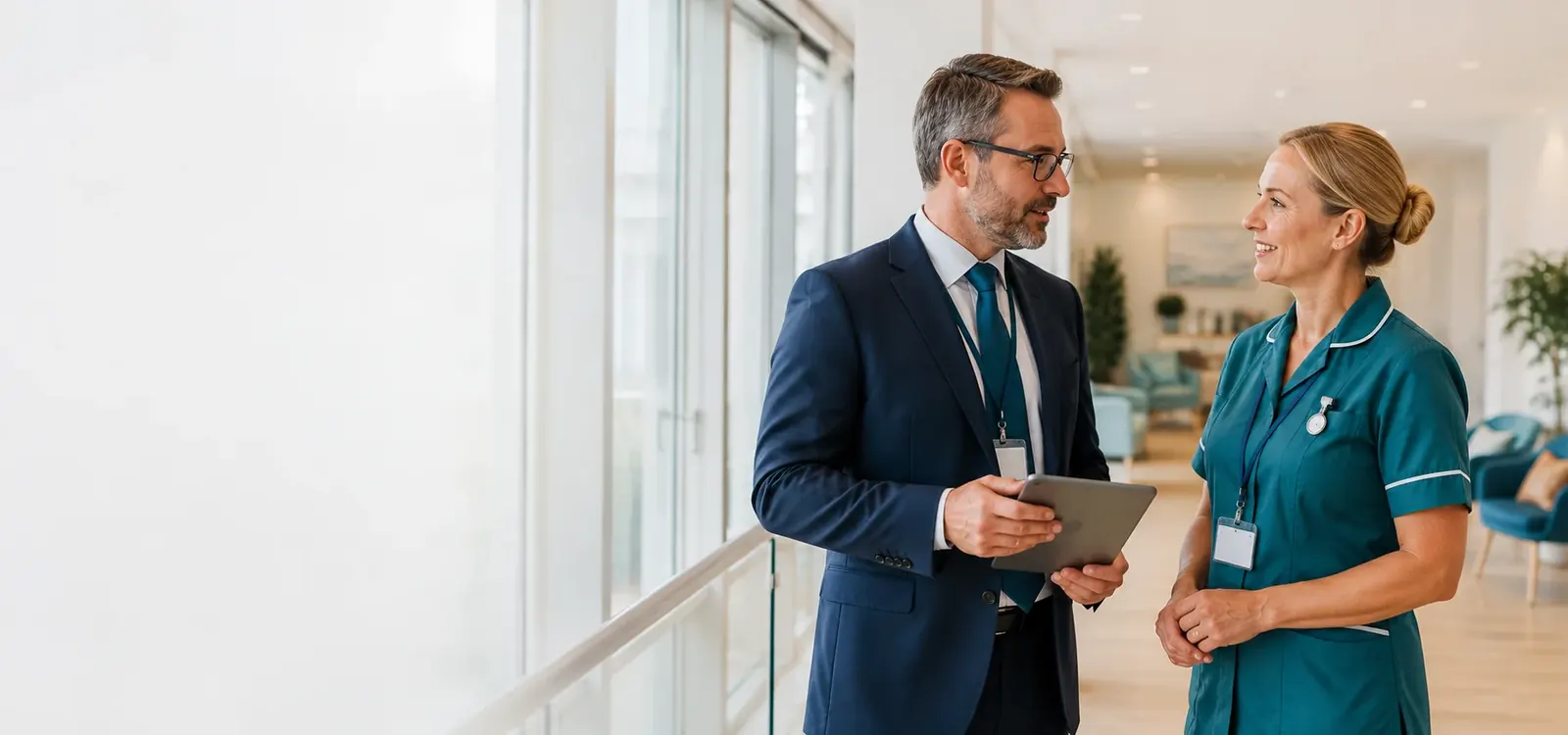 A healthcare executive and a nurse talking in a bright hallway